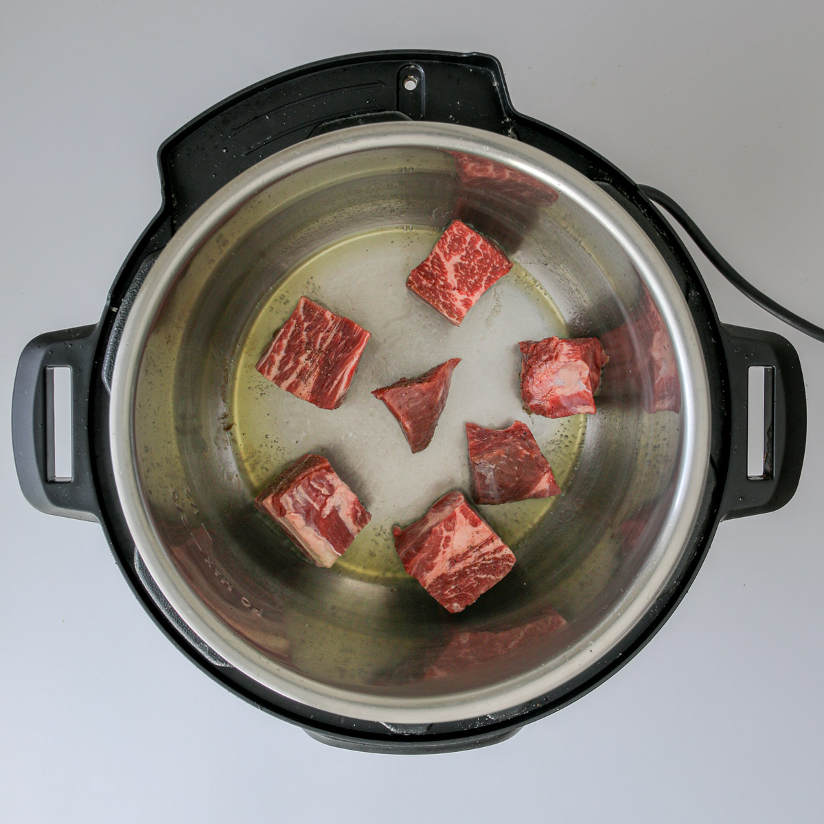raw meat cubes in hot oil in pressure cooker.
