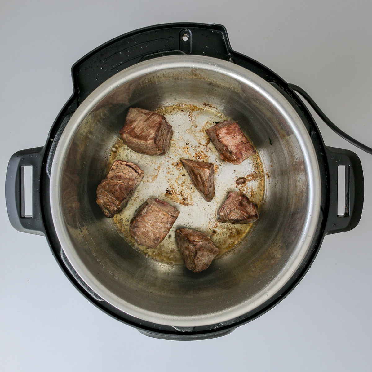 browned meat cubes in pressure cooker.