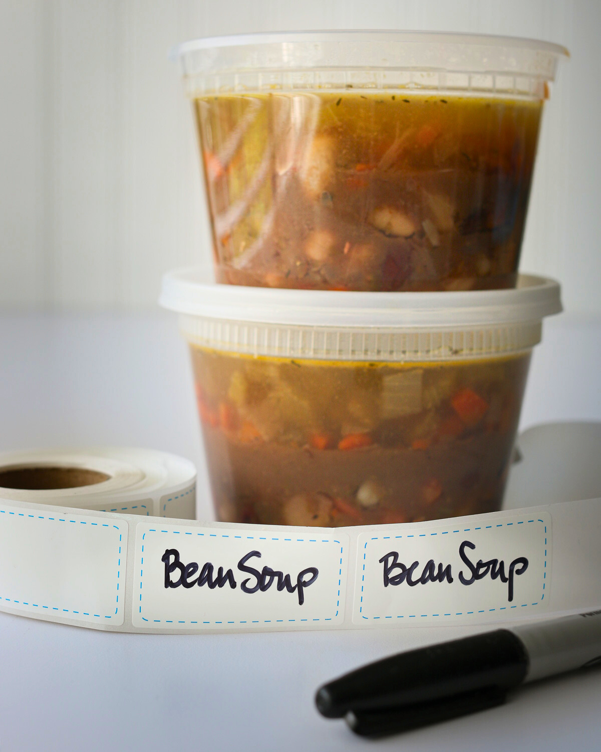 bean soup in freezer containers with labels on white counter.