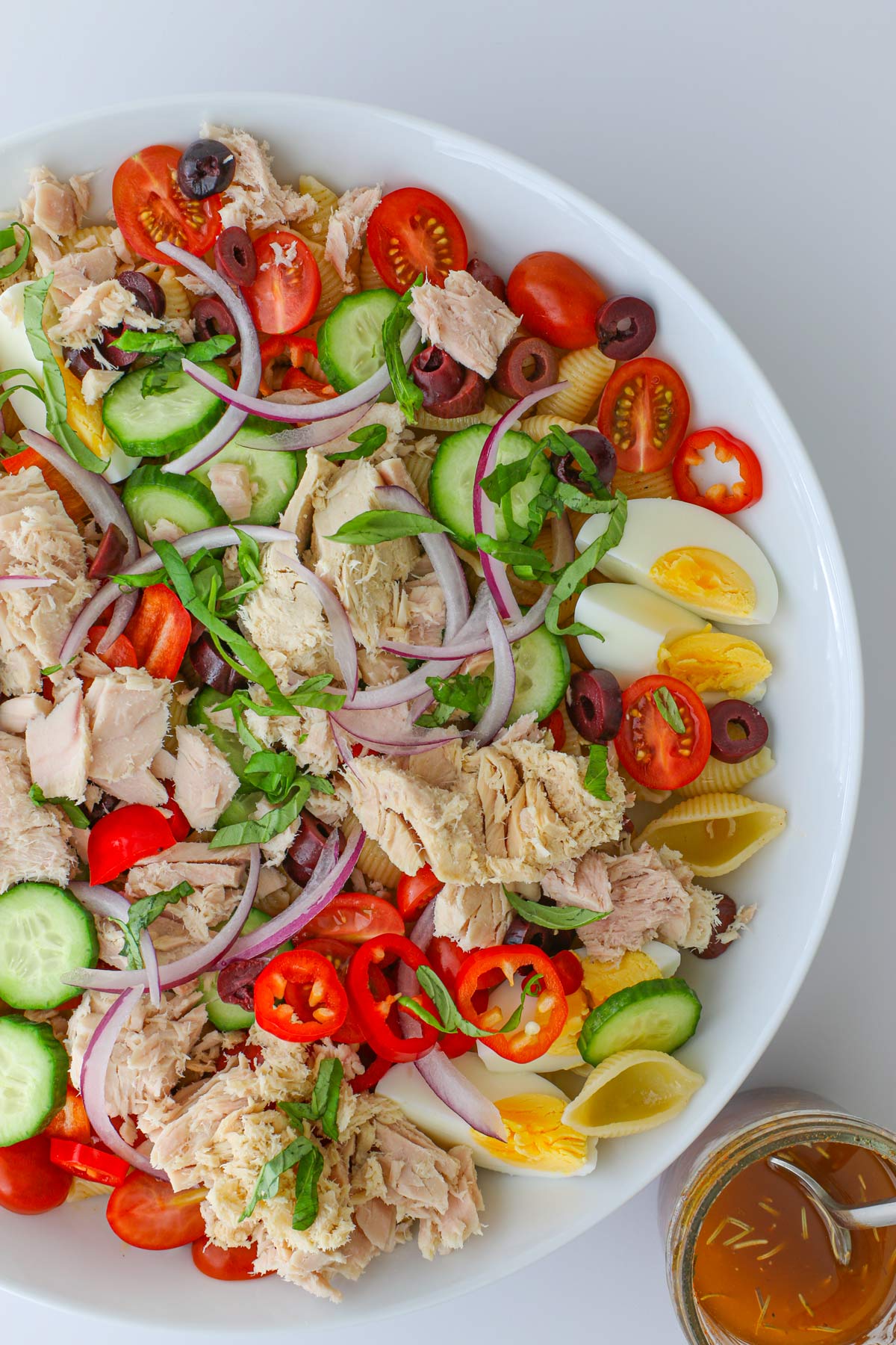 platter of tuna pasta salad with a jar of dressing on the side.