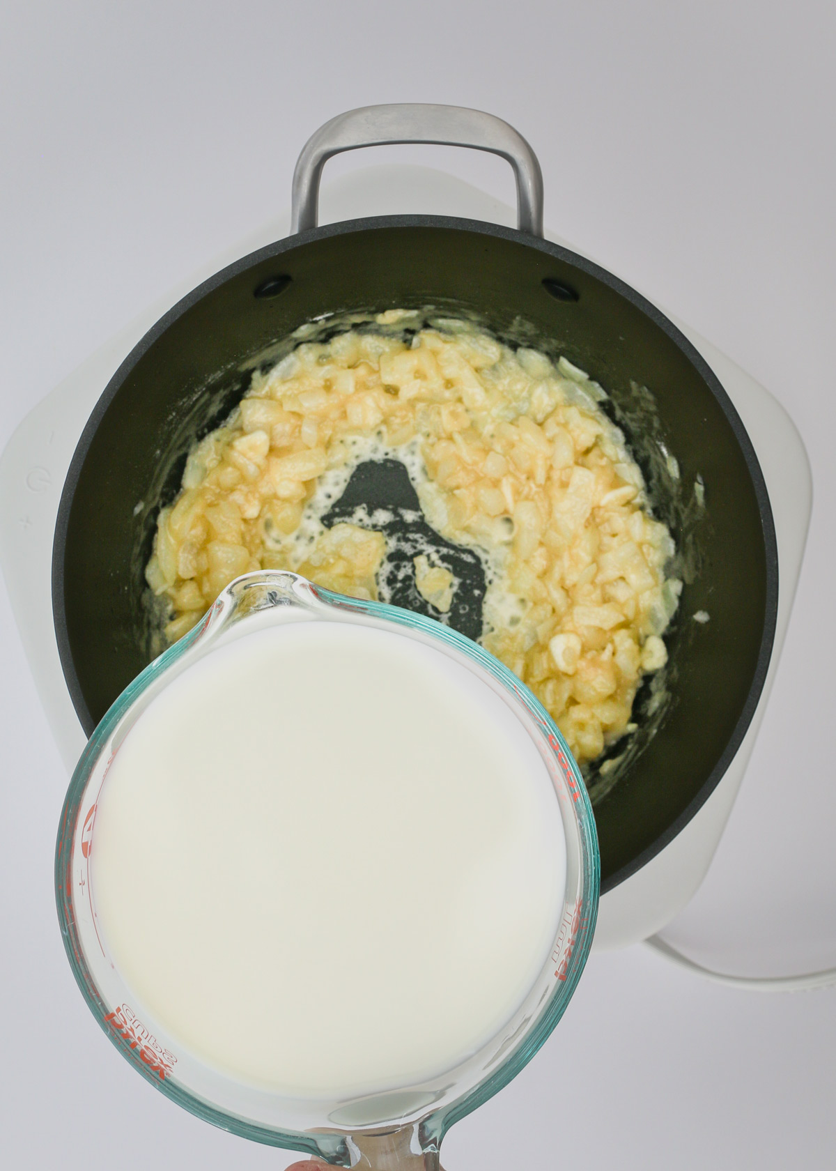 adding milk to make a sauce in the pot.