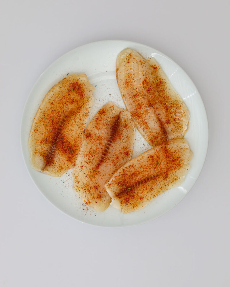 fish fillets on a plate, coated with seasoning mix.