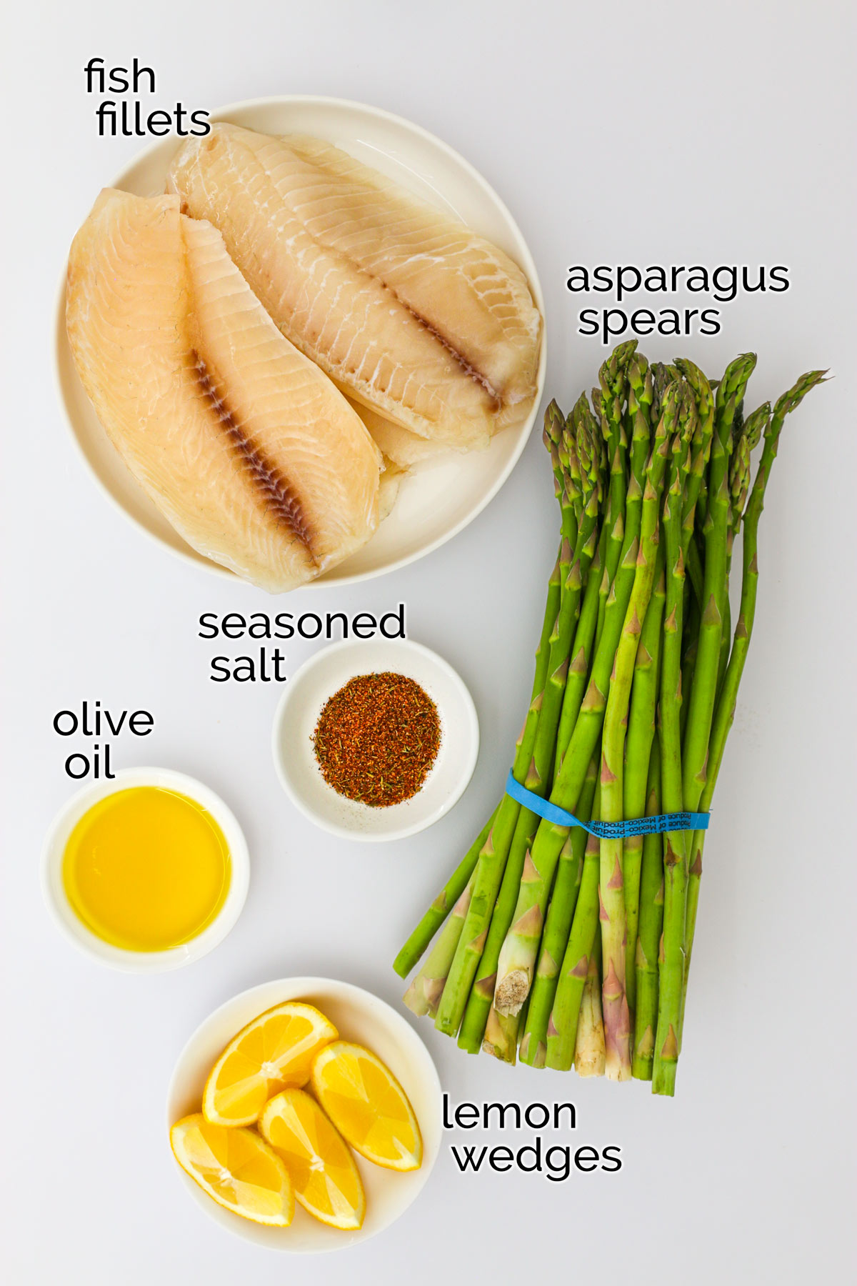 ingredients to make fish and asparagus laid out on a white counter.