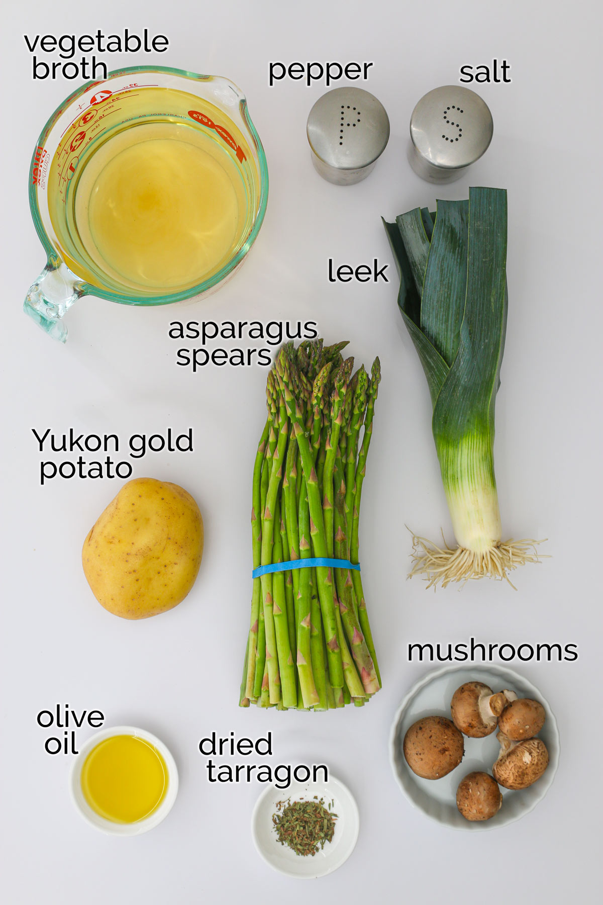 ingredients to make asparagus soup laid out on a white counter.