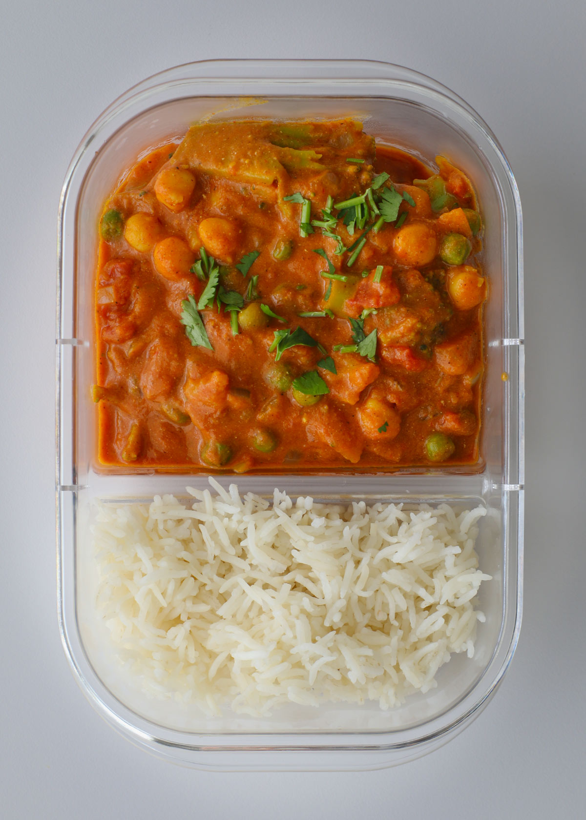 meal prep container with white rice on one side of the divider and veggie curry on the other.