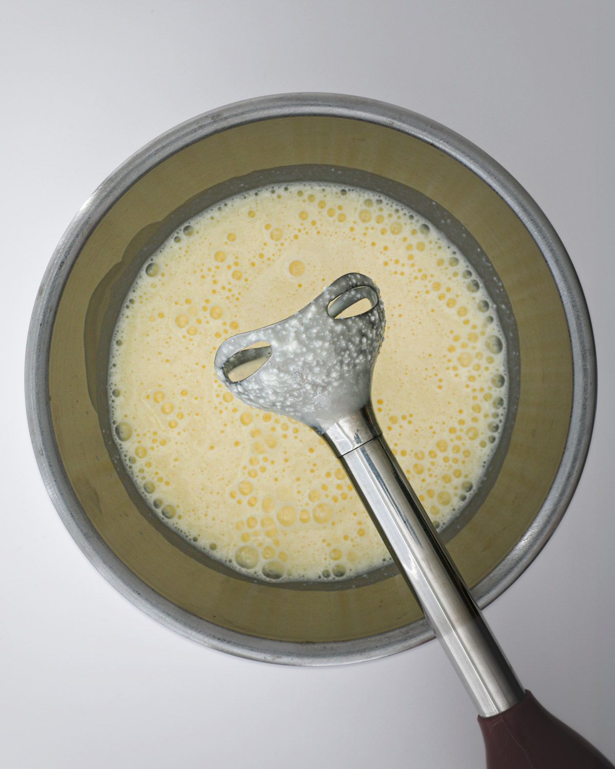 immersion blender held above bowl with blended cheese mixture.