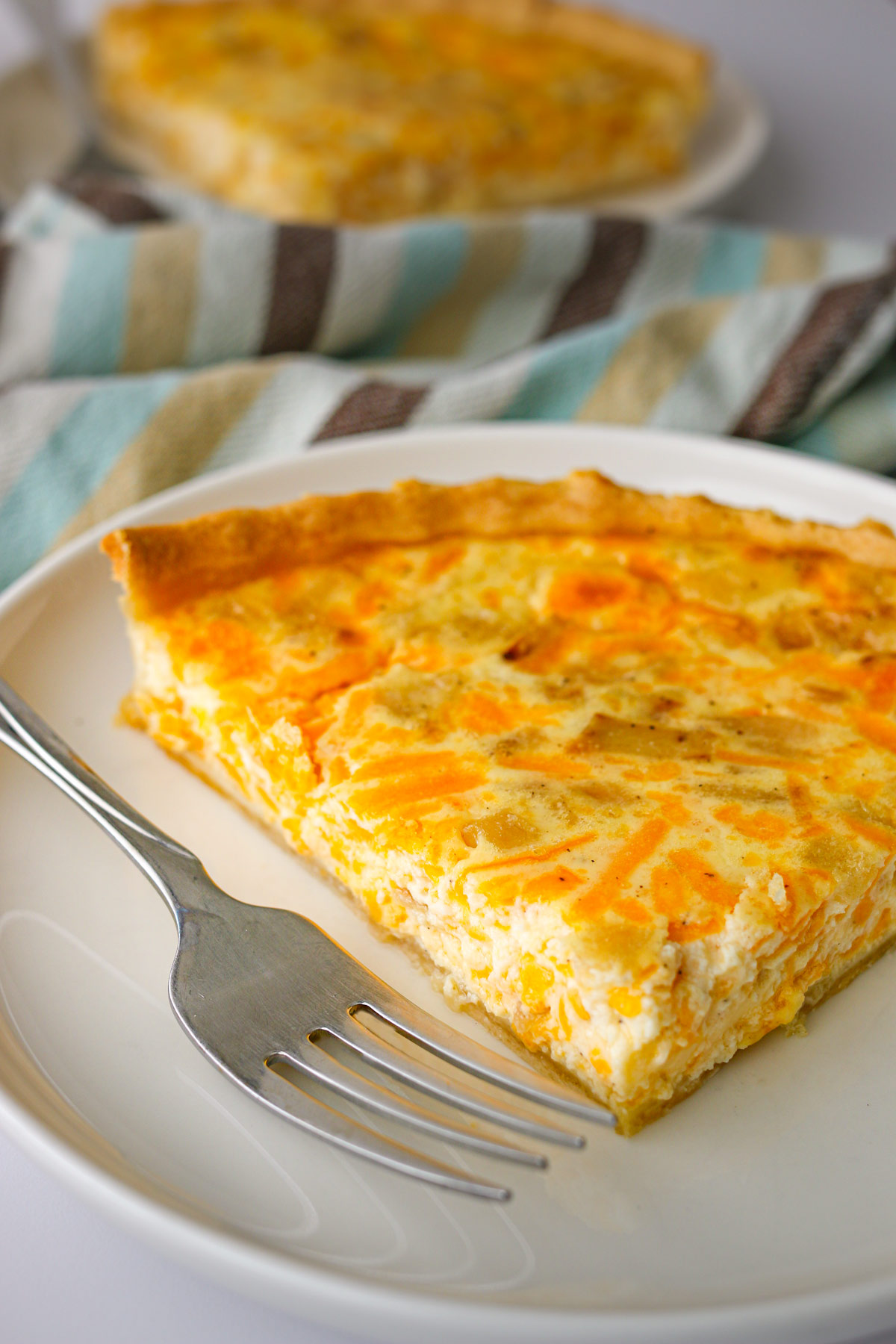 slice of quiche on a plate with a fork.