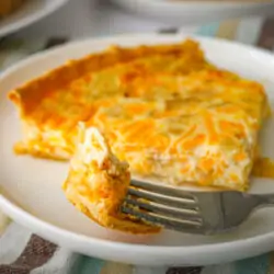 a bite of cottage cheese quiche on a fork next to a larger slice.