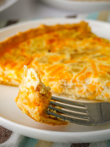 a bite of cottage cheese quiche on a fork next to a larger slice.