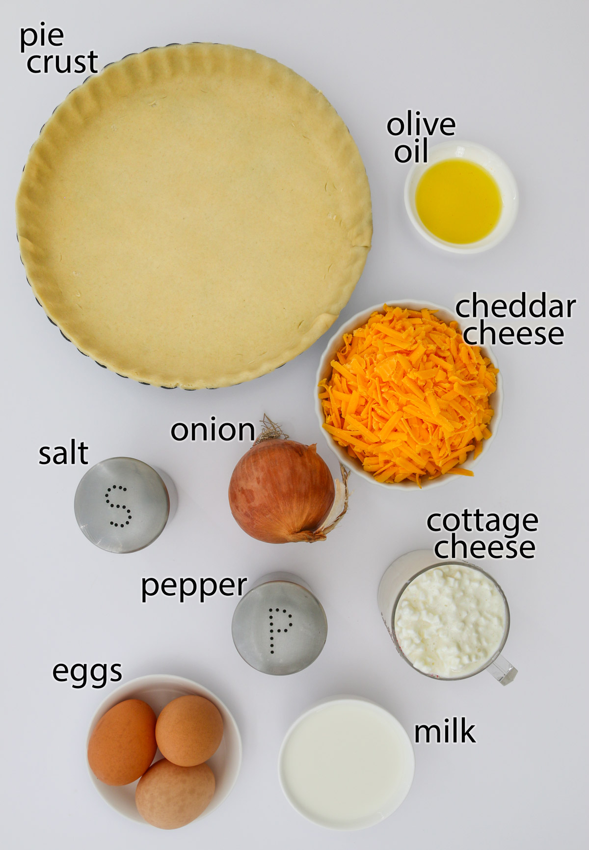 ingredients for cottage cheese quiche laid out on a white work surface.