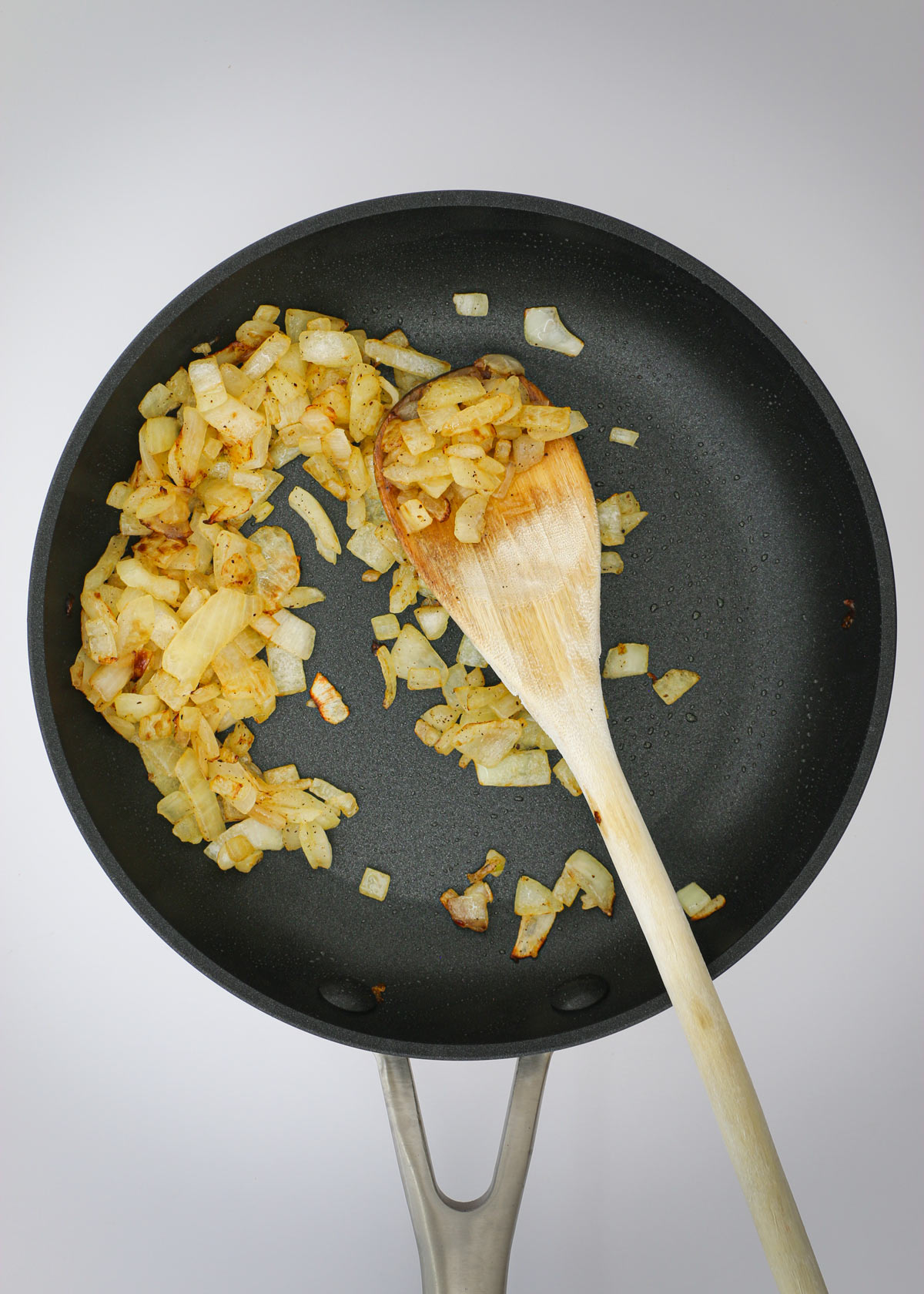 sautéed onions in skillet with wooden spoon.