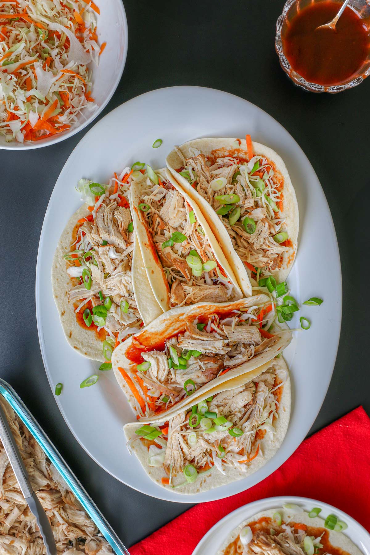 a platter with moo shu chicken on tortillas with toppings surrounding the platter.