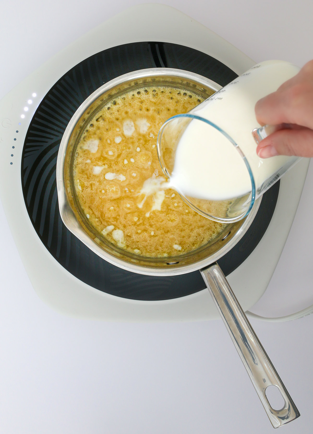 adding milk to the roux in the saucepan.