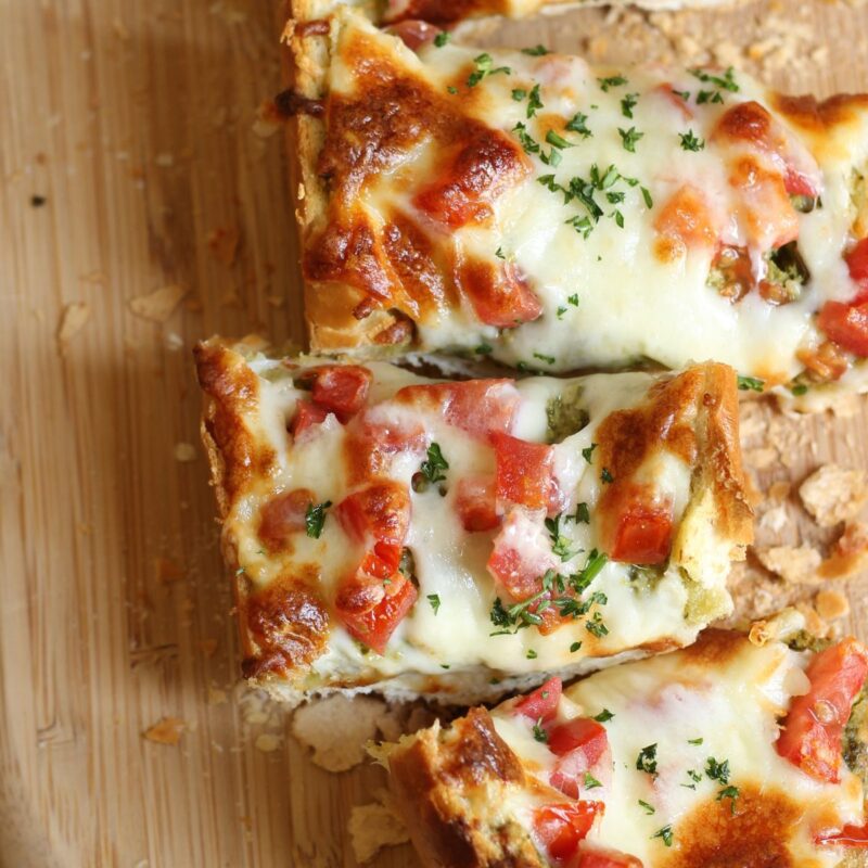 slices of french bread pizza on a wooden board.