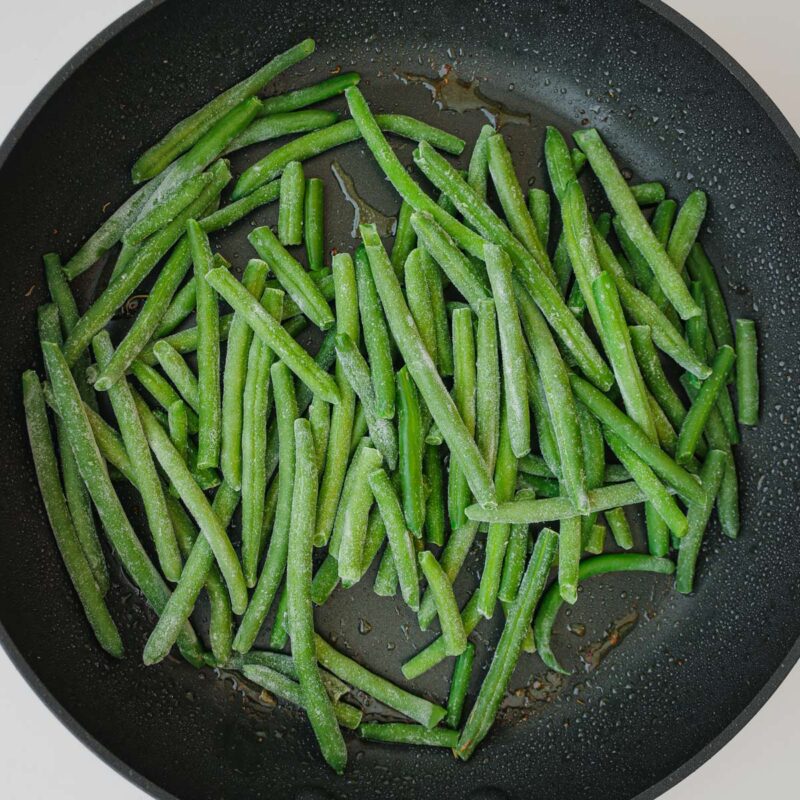 green beans cooking in the skillet drippings.