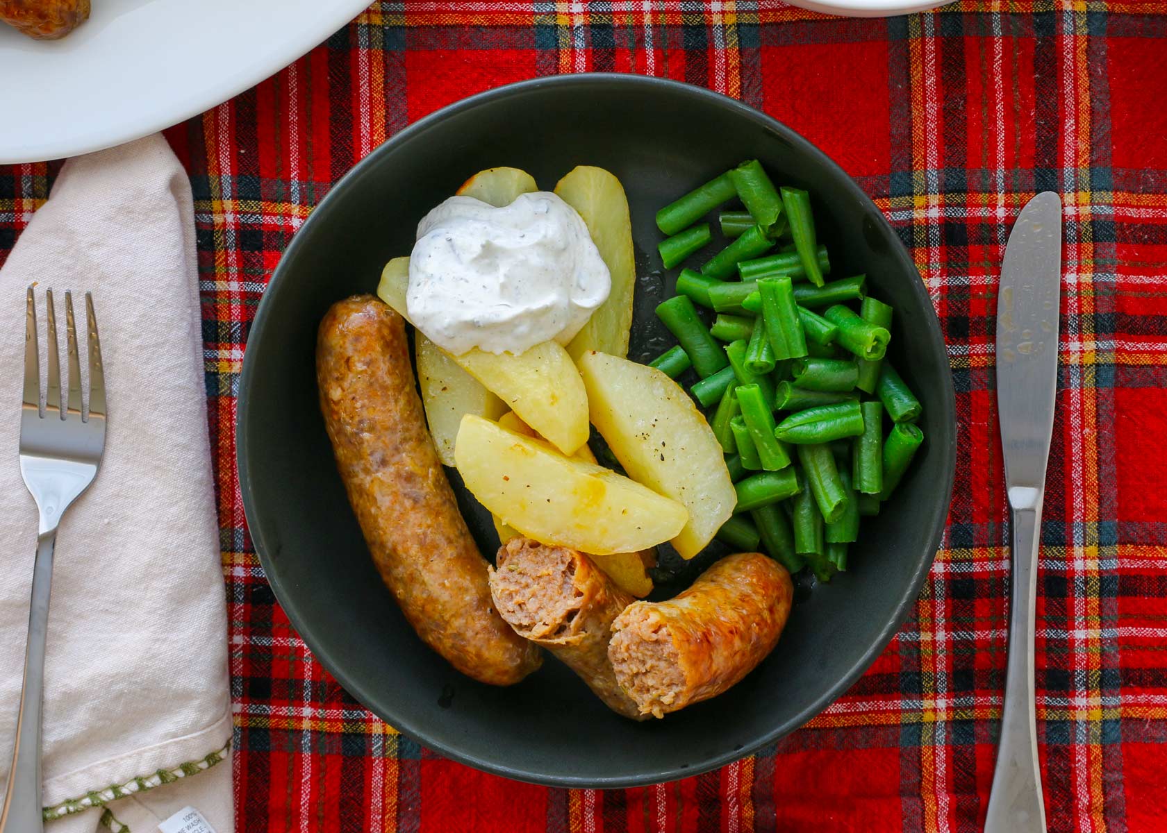 dinner plate with sausage, potatoes, and green beans with sour cream sauce.