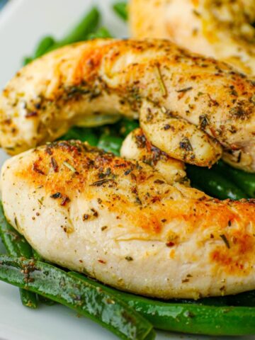 close up of chicken and green beans on white platter.