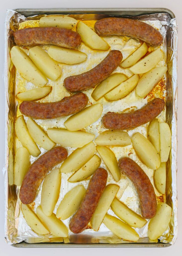 cooked potatoes and sausage on baking pan.