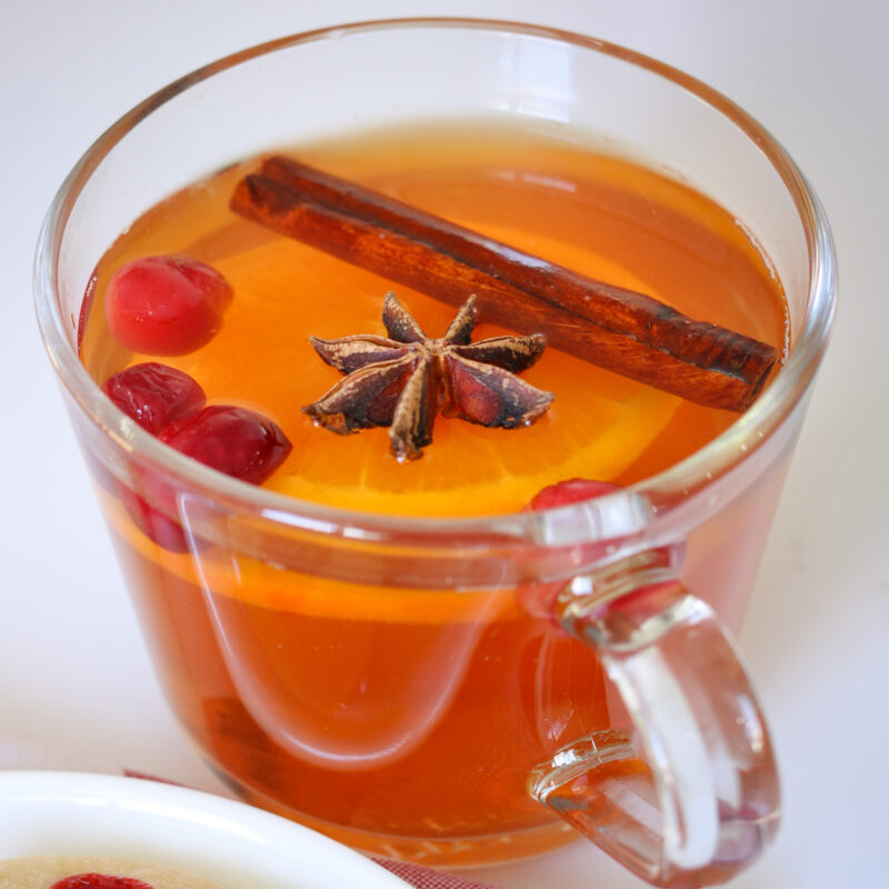 glass mug of wassail with garnishes floating in it.