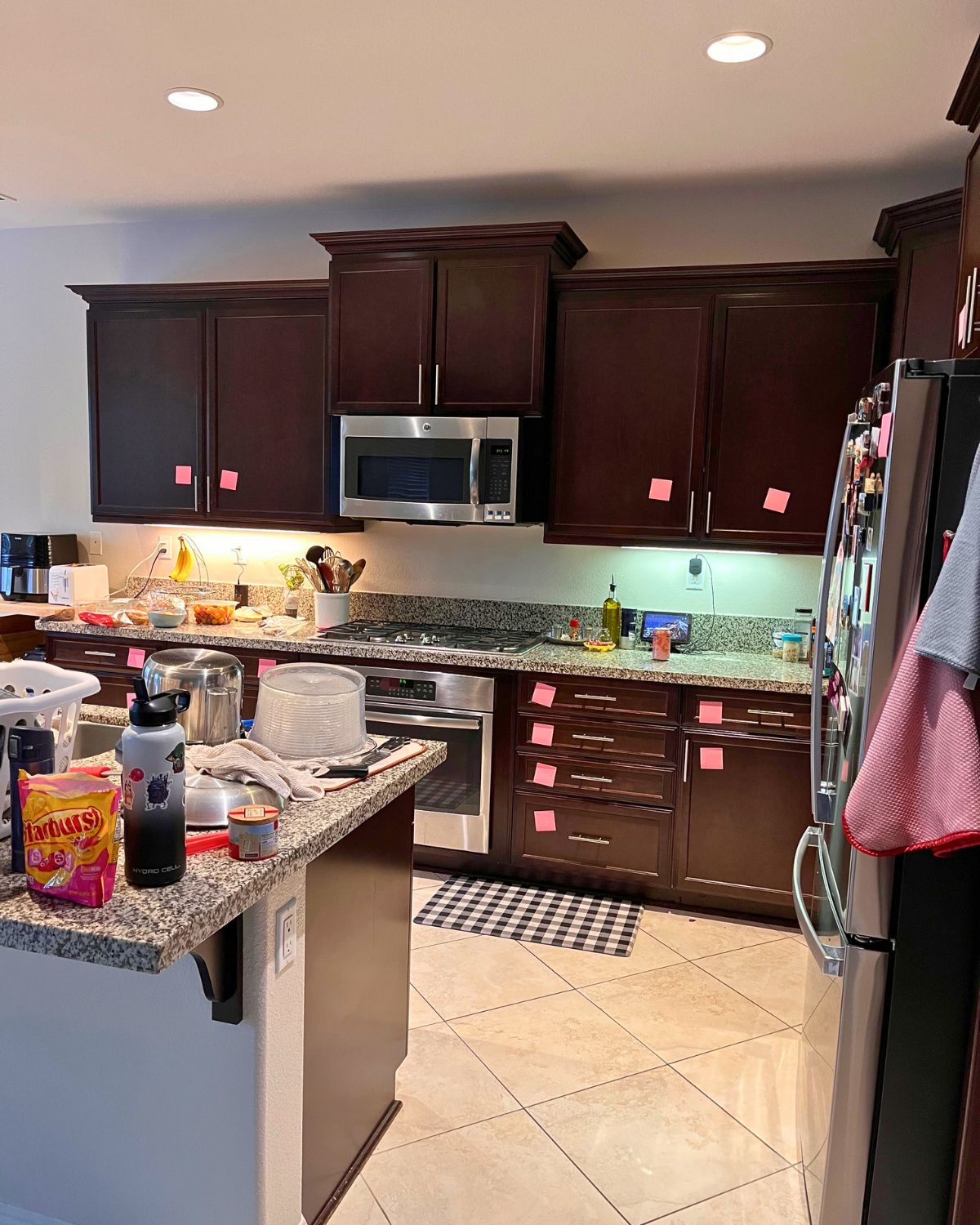 kitchen cabinets with pink post-it notes on them.