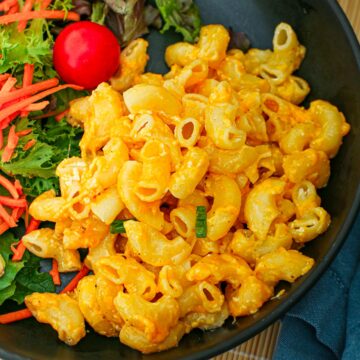 close up of Mac and cheese on a black plate.