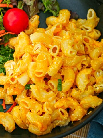 close up of Mac and cheese on a black plate.