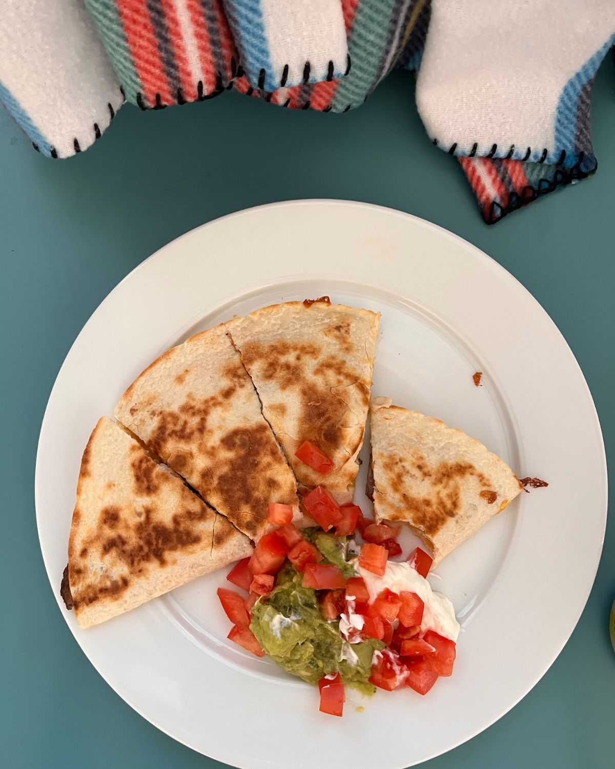 steak quesadilla on plate with yogurt and guacamole and diced tomatoes.