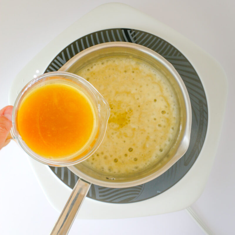 pouring broth into roux in saucepan.