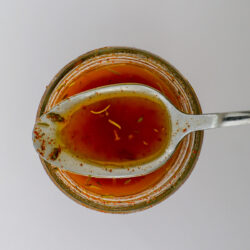 spoonful of basic vinaigrette resting on jar of dressing.