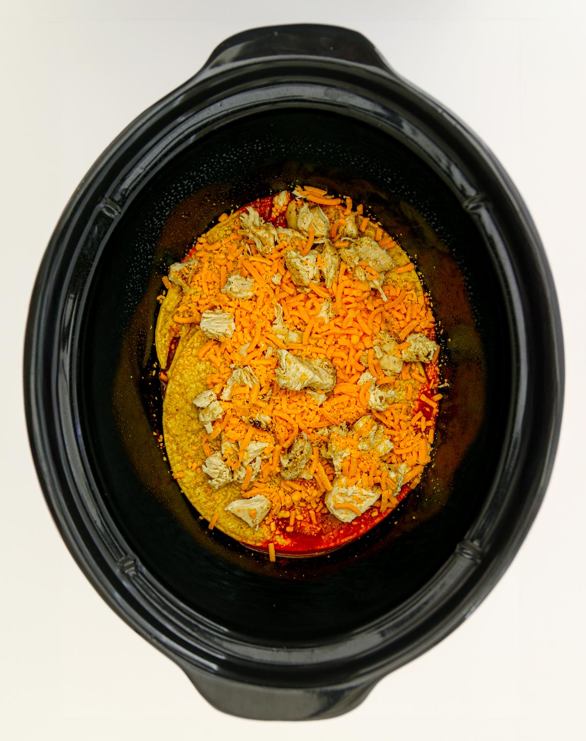 tortillas, chicken, and cheese layered in the crock.
