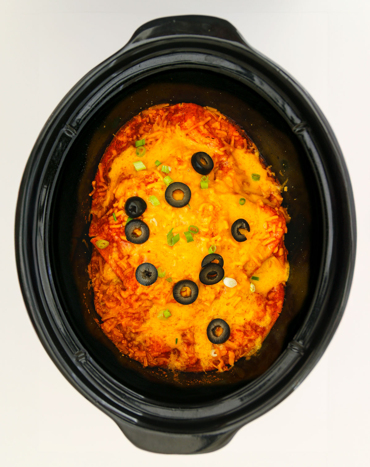 the finished dish in the crockpot, topped with sliced black olives.