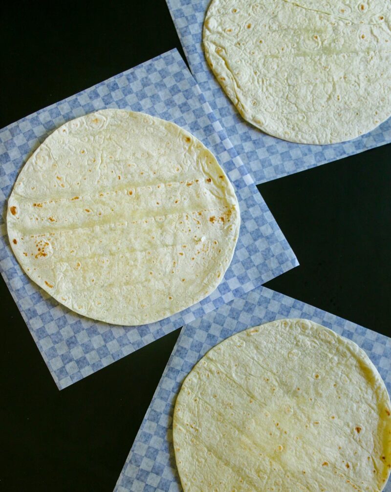 deli papers and tortillas laid out on work surface.