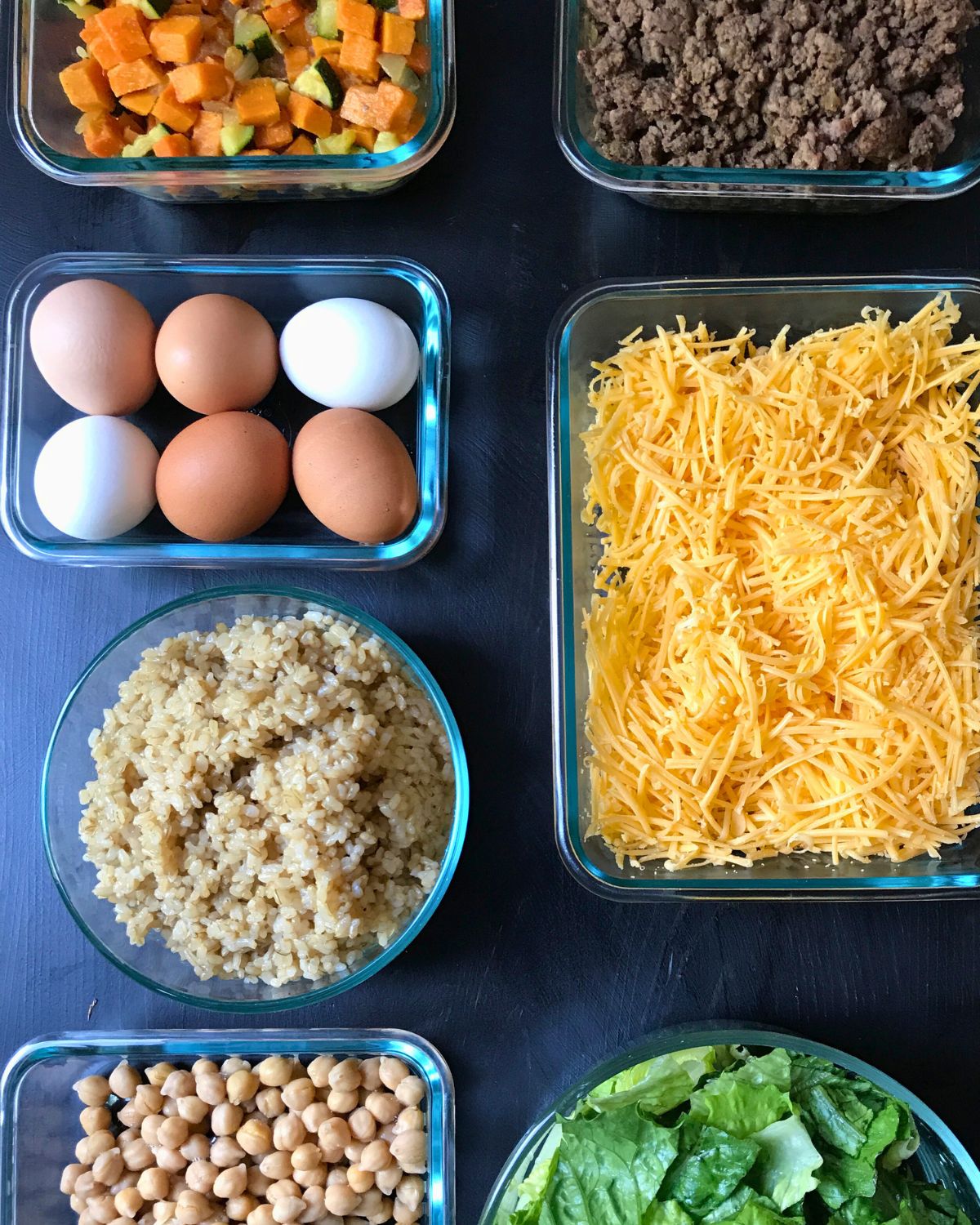 array of meal prepped components on black table.