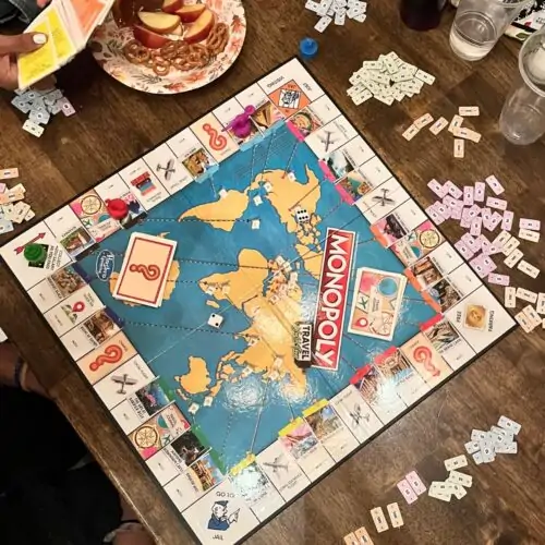 monopoly game on table with snacks nearby.