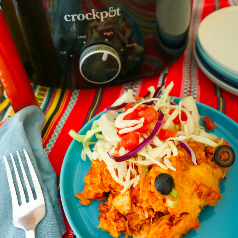crockpot next to plate of enchiladas with cabbage topping.