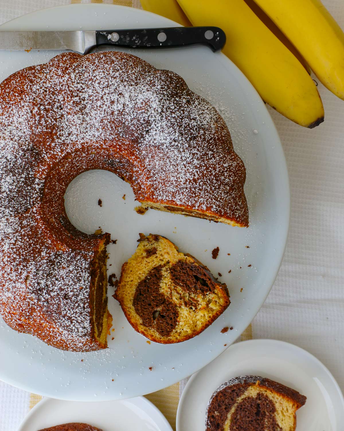 cake, sprinkled with powdered sugar and sliced on a cake plate with one slice lying down.