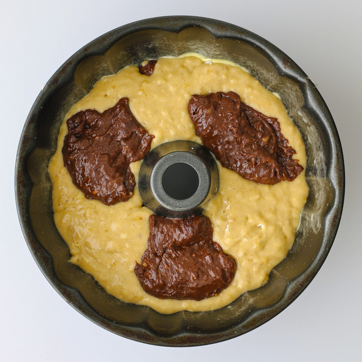 banana and chocolate batters alternating in the prepared bundt pan.