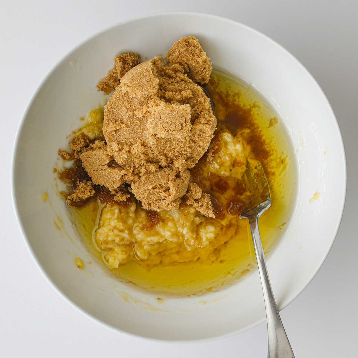 oil, sugar, and bananas in white bowl.