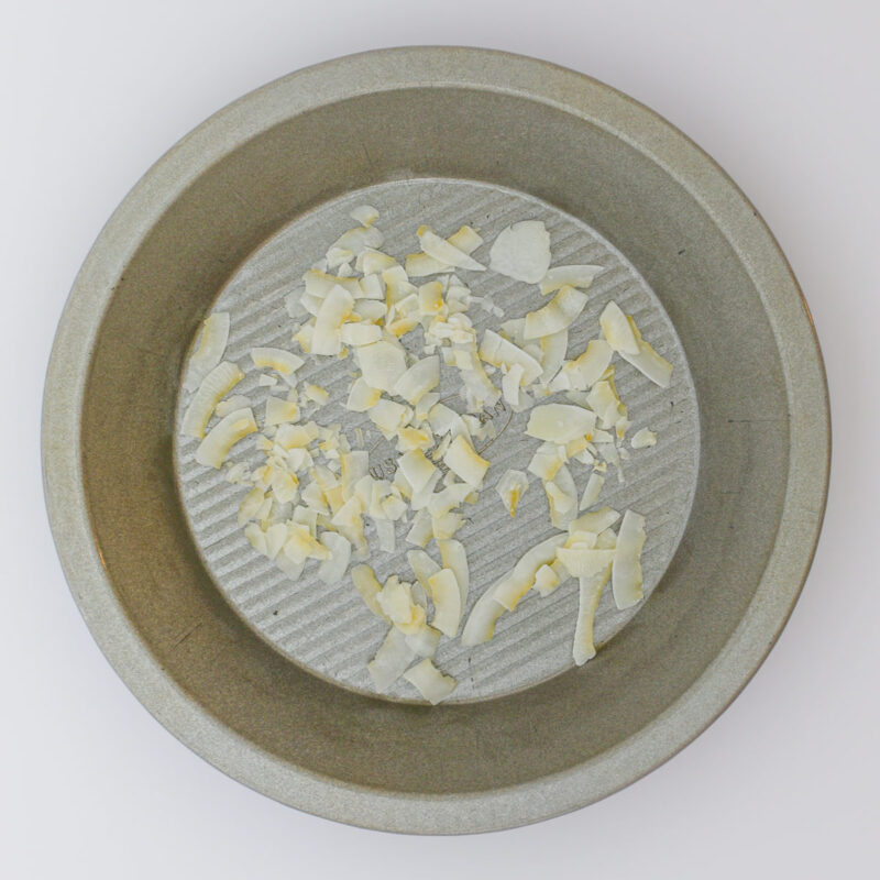 coconut chips in pie plate on white table.