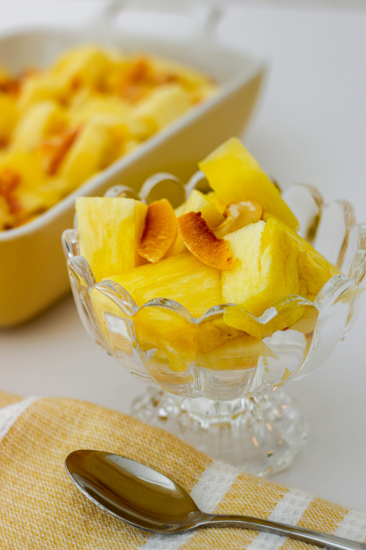pineapple salad in a cut glass dish with a yellow napkin and spoon nearby.