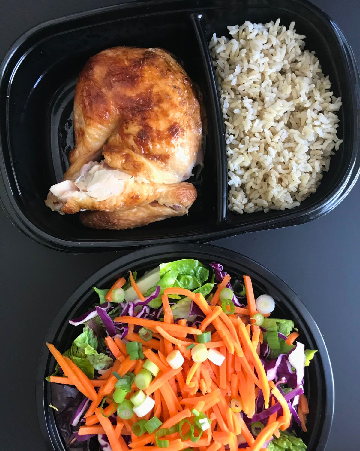meal prep boxes with chicken, rice, and salad.