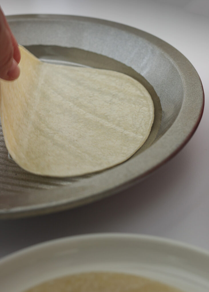 dipping tortilla in pie plate of water.