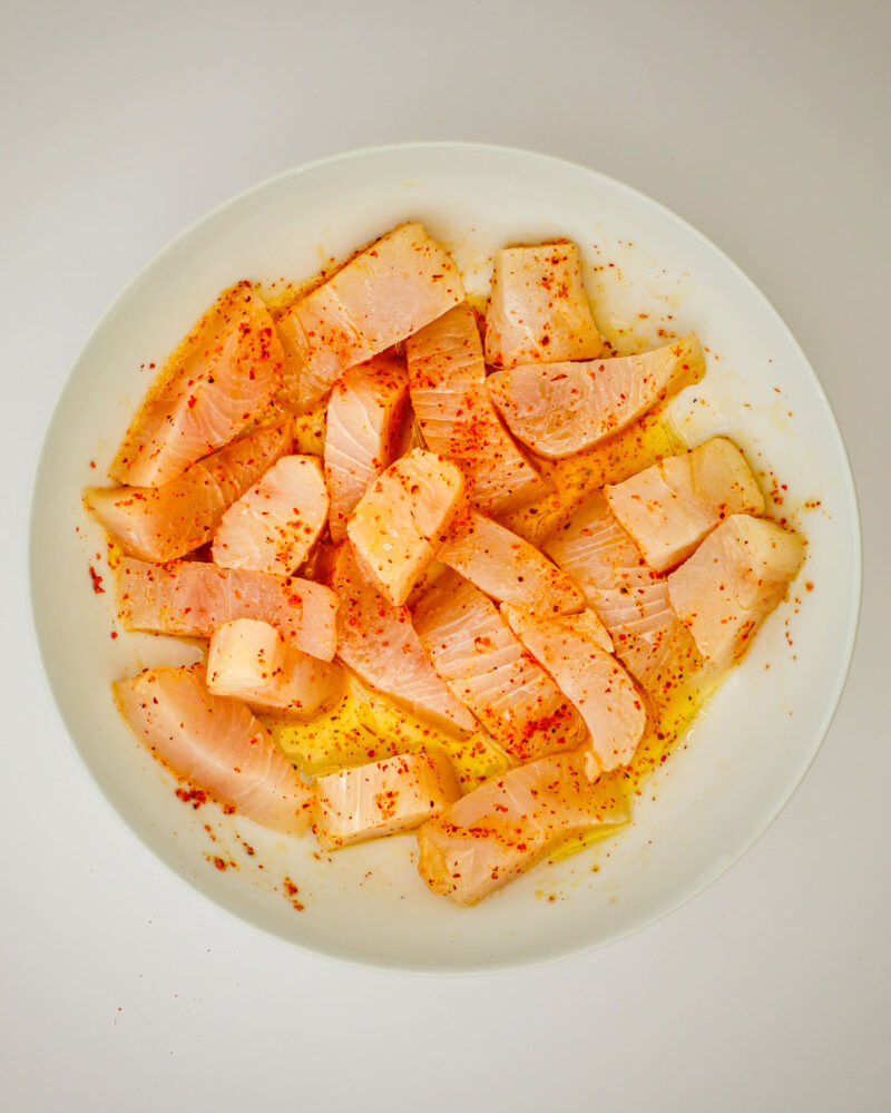 fish chunks tossed with oil and tajin in a bowl.