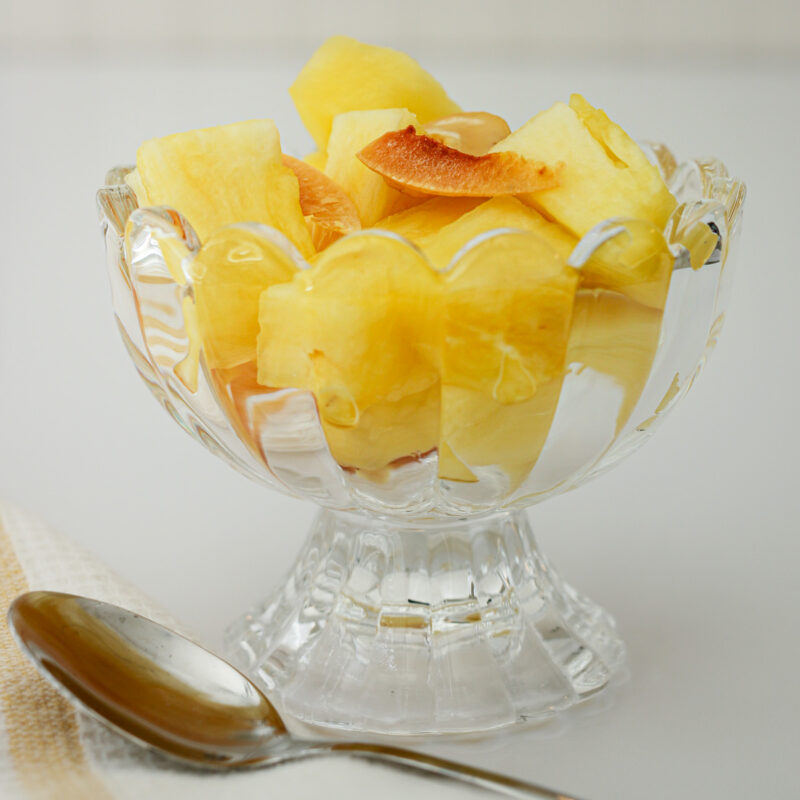 close up of pineapple salad in cut glass dish with spoon nearby.