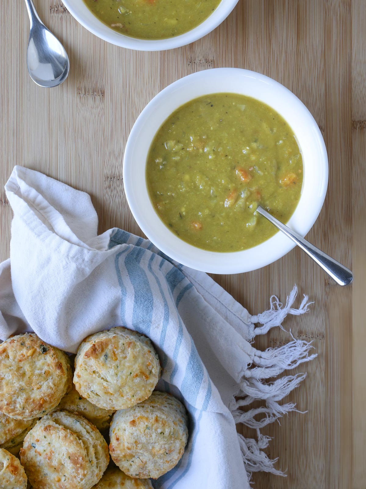 bowl of split pea soup next of basket of cheesy biscuits.
