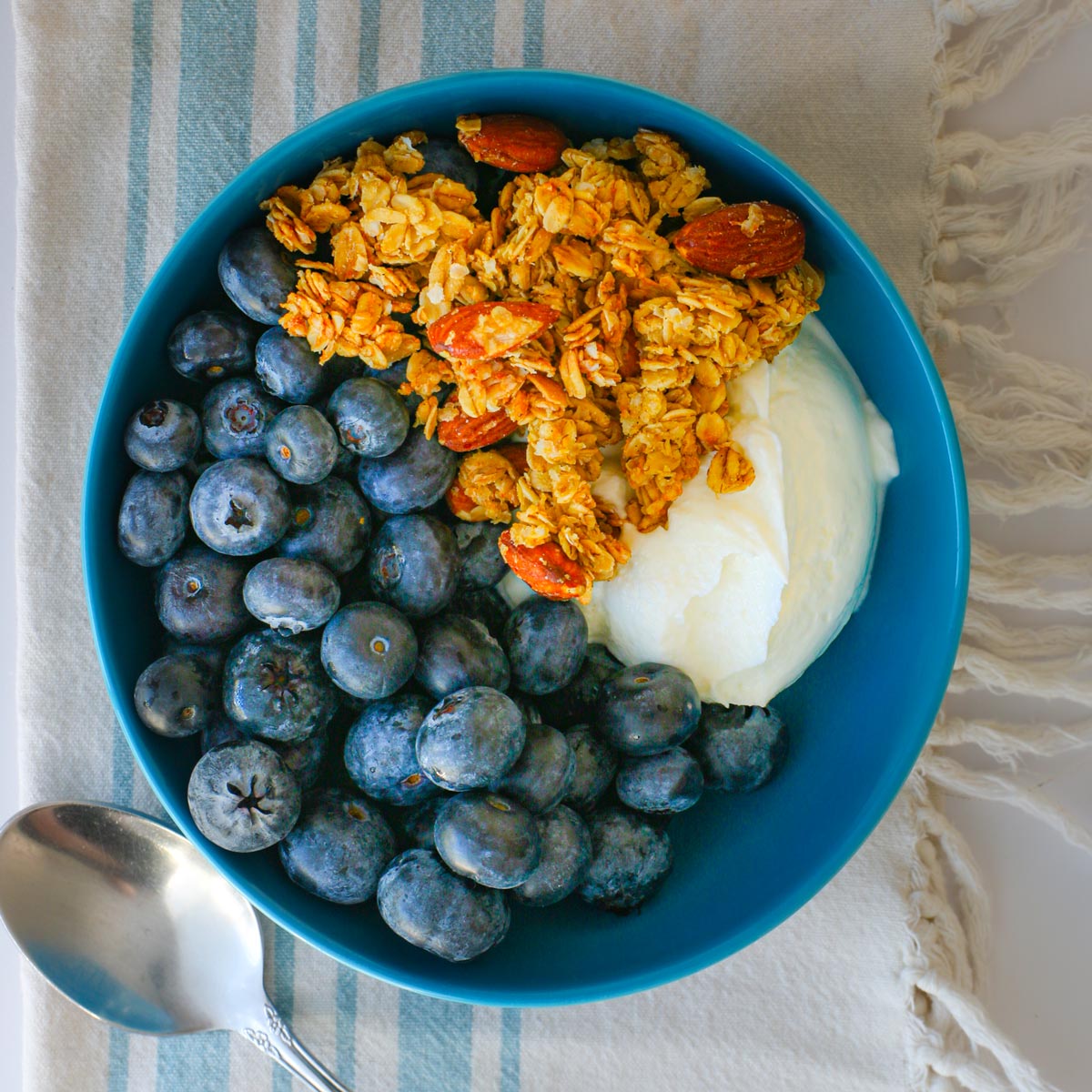 vanilla almond granola atop a yogurt and blueberry bowl.