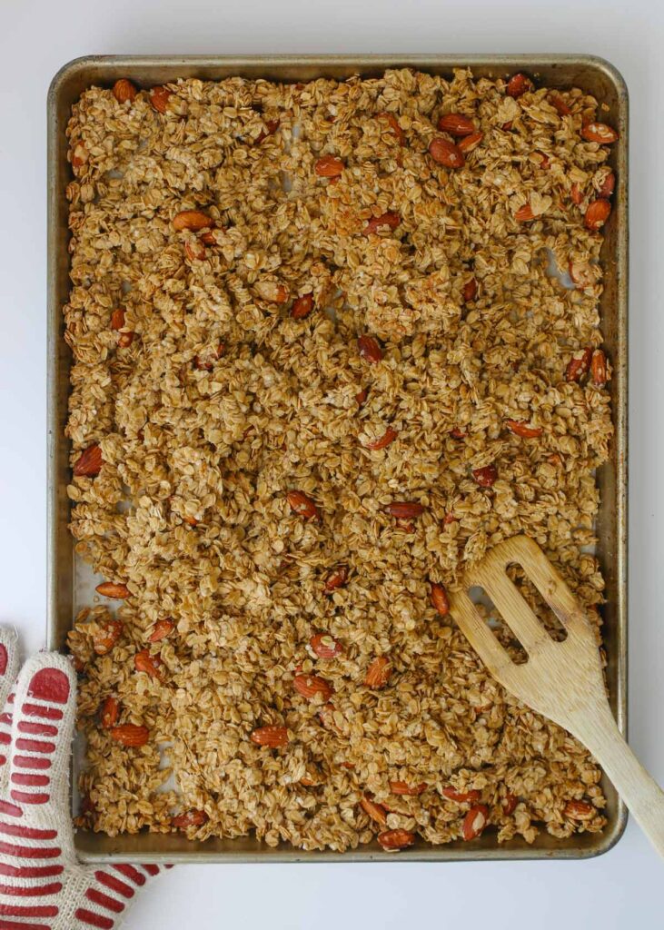breaking the semi-baked granola into clusters with a wooden spatula.