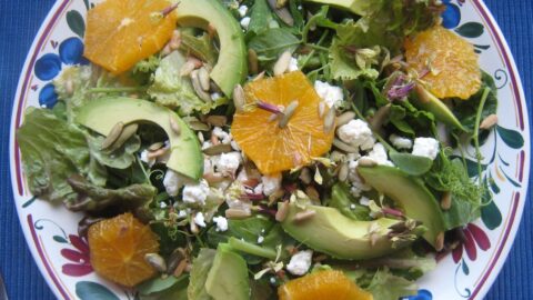 avocado and orange salad on blue counter.