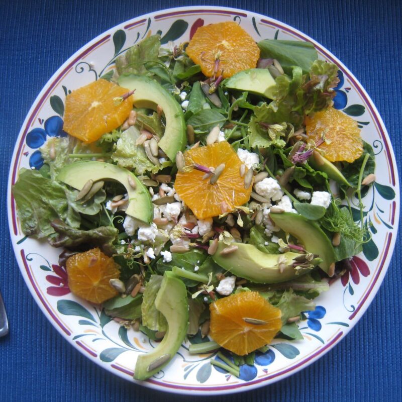 avocado and orange salad on blue counter.