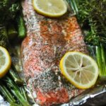 baked salmon in large foil pack with broccolini and lemon slices.